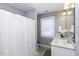 A well-lit bathroom with a double sink vanity, tile flooring, and shower with white shower curtain at 870 Live Oak Ln, Nashville, NC 27856
