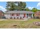 Charming single-story home featuring red shutters, a red front door, and meticulously landscaped front yard at 1007 Ancroft Ave, Durham, NC 27713