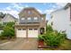 Charming two-story brick home featuring a two-car garage, manicured landscaping, and a welcoming front entrance at 1030 Thoughtful Spot Ln, Durham, NC 27703
