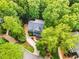 Aerial view showcases a green home nestled in a dense canopy of trees, with a winding driveway at 104 Windorah Place Pl, Chapel Hill, NC 27517