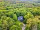 Aerial shot showing a green home surrounded by lush, mature trees and a curving driveway at 104 Windorah Place Pl, Chapel Hill, NC 27517