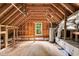 Unfinished attic space with a window, exposed wooden beams, and a water heater at 104 Windorah Place Pl, Chapel Hill, NC 27517