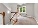 Carpeted hallway with a wooden staircase, white railing, large window and bright natural light at 104 Windorah Place Pl, Chapel Hill, NC 27517