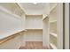 Bright walk-in closet featuring custom shelving and wooden clothing rods for optimal storage solutions at 104 Windorah Place Pl, Chapel Hill, NC 27517