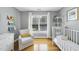 Bright Bedroom with hardwood floors, a white crib, comfortable chair, and natural light from a large window at 106 Bluefield Rd, Chapel Hill, NC 27517