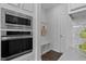 A modern kitchen with stainless steel appliances, white cabinets and a functional mud room area at 108 Valley View Dr, Chapel Hill, NC 27516