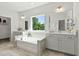 Bright bathroom featuring a garden tub, separate vanities, large mirrors and a window offering natural light at 108 Valley View Dr, Chapel Hill, NC 27516