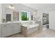 Bright bathroom with a garden tub, double vanity sinks, large mirrors, and a window offering natural light at 108 Valley View Dr, Chapel Hill, NC 27516