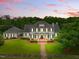 Stately white home with black shutters, columns, and a manicured lawn under a stunning pink and purple sunset sky at 1093 N Lakeside Dr, Smithfield, NC 27577