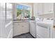 Well-lit laundry room with utility sink, ample cabinets, and modern washer and dryer at 1093 N Lakeside Dr, Smithfield, NC 27577