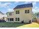 View of the home's rear facade featuring a sunroom, lush lawn, and light yellow vinyl siding at 1148 Dexter Ridge Dr, Holly Springs, NC 27540