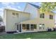 View of the home's rear facade featuring a sunroom, lush lawn, and light yellow vinyl siding at 1148 Dexter Ridge Dr, Holly Springs, NC 27540
