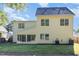 View of the home's rear facade featuring a sunroom, lush lawn, and light yellow vinyl siding at 1148 Dexter Ridge Dr, Holly Springs, NC 27540