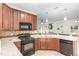Well-equipped kitchen with granite countertops, wood cabinets, and modern black appliances at 1148 Dexter Ridge Dr, Holly Springs, NC 27540