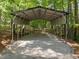 Metal carport in wooded area featuring a gravel floor and a metal roof at 120 Harmony Hill Ln, Cary, NC 27513