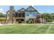 Expansive backyard featuring a stone fireplace, outdoor kitchen, screened-in porch, and manicured lawn at 12317 Richmond Run Dr, Raleigh, NC 27614
