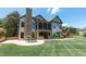 Expansive backyard featuring a stone fireplace, outdoor kitchen, screened-in porch, and manicured lawn at 12317 Richmond Run Dr, Raleigh, NC 27614