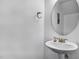 Simple powder room features a pedestal sink, round mirror, and neutral tones at 140 Sunstone Dr, Cary, NC 27519