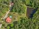 Aerial view of red-roofed house with pool, outbuildings, pond, garden, and surrounded by mature trees at 1656 Nc-42 Hwy, Moncure, NC 27559