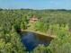 Aerial view of house near pond, all surrounded by lush green trees on a sunny day at 1656 Nc-42 Hwy, Moncure, NC 27559