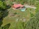 Aerial view of a charming home with a red roof, surrounded by lush greenery and an above-ground pool at 1656 Nc-42 Hwy, Moncure, NC 27559