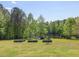 Tranquil backyard featuring raised garden beds, mature trees, open lawn space, and a peaceful view of the water at 1656 Nc-42 Hwy, Moncure, NC 27559