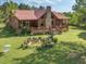 Aerial view showcasing a log cabin home with a stone chimney, front porch, water garden, and lush yard at 1656 Nc-42 Hwy, Moncure, NC 27559