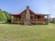 Exterior showcasing a log cabin home with a stone chimney, front porch, and lush yard at 1656 Nc-42 Hwy, Moncure, NC 27559