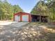 Large red metal garage with two bays, basketball hoop, and storage area in a wooded setting at 1656 Nc-42 Hwy, Moncure, NC 27559