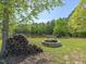 Serene outdoor space featuring a stone firepit and stacked logs by a tranquil pond at 1656 Nc-42 Hwy, Moncure, NC 27559