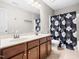 Well-lit bathroom featuring a double vanity, floral shower curtain and tiled floors at 1719 Willowcrest Rd, Durham, NC 27703