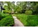Serene backyard featuring a lush green lawn, mature trees, and a stone walkway leading to the house at 1904 Victoria Rd, Raleigh, NC 27608