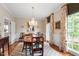Formal dining room with hardwood floors, chandelier, and elegant curtains framing a bright window at 1904 Victoria Rd, Raleigh, NC 27608