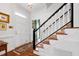 Elegant foyer with hardwood floors, white staircase with black railing, and decorative chandelier at 1904 Victoria Rd, Raleigh, NC 27608