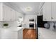 Bright kitchen featuring white cabinetry, stainless steel appliances, and hardwood floors at 1904 Victoria Rd, Raleigh, NC 27608