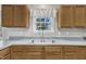 Close-up of a well-maintained kitchen featuring updated gray countertops, natural wood cabinets, and stainless steel sink at 2037 Summer Shire Way, Raleigh, NC 27604