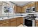 Modern kitchen equipped with stainless steel appliances, gray countertops, and natural wood cabinetry at 2037 Summer Shire Way, Raleigh, NC 27604