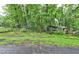 View of a lush, treed front yard with a small outdoor building with a chimney visible at 205 Bruton Dr, Chapel Hill, NC 27516