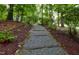 Woodland walkway with natural wood steps leads to the home, surrounded by foliage at 205 Bruton Dr, Chapel Hill, NC 27516