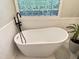 Bright bathroom featuring a freestanding tub with black fixtures and a unique glass block window at 206 Lilliput Ln, Wake Forest, NC 27587