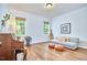 Well-lit living room featuring wood floors, two windows, a sofa, and a piano at 210 Bennington Pkwy, Durham, NC 27713