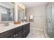 Bathroom featuring double vanity, dark wood cabinets, large mirrors, and a glass door shower at 3034 Raddercrest Ct, Fuquay Varina, NC 27526