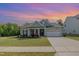 Charming home with a two-car garage, manicured lawn, and a lovely front porch under a colorful evening sky at 3034 Raddercrest Ct, Fuquay Varina, NC 27526