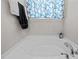 This bright white bathroom features a soaking tub with chrome fixtures, towel rack, and blue patterned window treatment at 325 Avery Glenn Way, Fuquay Varina, NC 27526