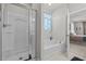 Bright, white bathroom features a clear glass shower stall, relaxing soaking tub, and light blue window treatment at 325 Avery Glenn Way, Fuquay Varina, NC 27526