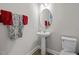 This powder room features a pedestal sink, oval mirror, and tiled floors, as well as colorful accent towels at 325 Avery Glenn Way, Fuquay Varina, NC 27526