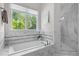 Soaking tub with decorative tile surround and large window with wooded view at 3913 Orchard Point Ct, Apex, NC 27539