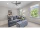 Comfortable living room with a gray couch, ottoman, and sun-lit windows showing lush green trees at 3913 Orchard Point Ct, Apex, NC 27539