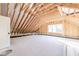 Large unfinished attic featuring wood framing, a window, and insulation, offering customization potential at 4009 Yates Mill Pond Rd, Raleigh, NC 27606