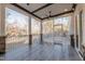 Covered porch with wood-look tile flooring, stone support columns, a ceiling fan, and views of the wooded backyard at 4009 Yates Mill Pond Rd, Raleigh, NC 27606